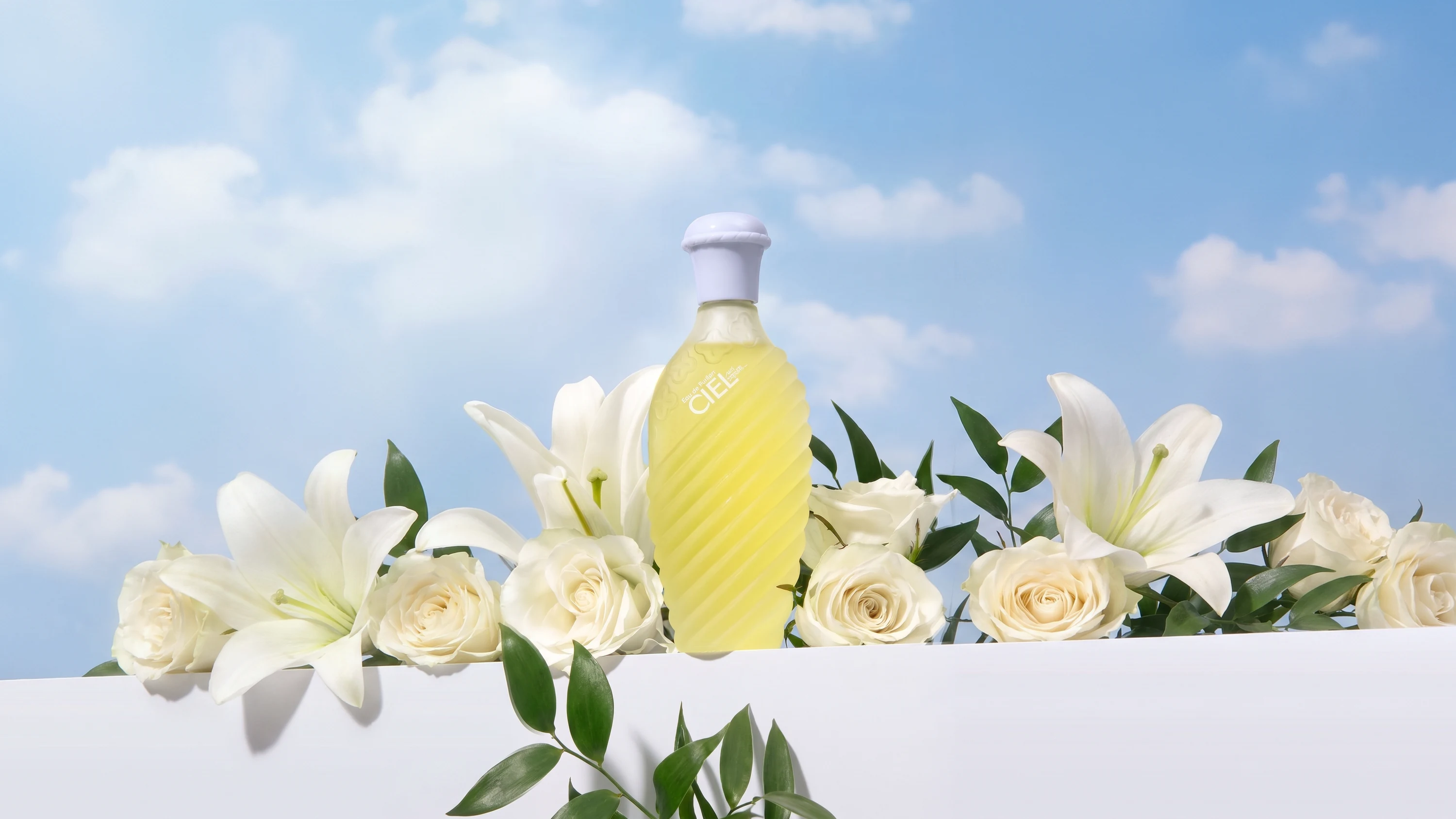 Ciel bottle with white lilies and roses against a blue sky